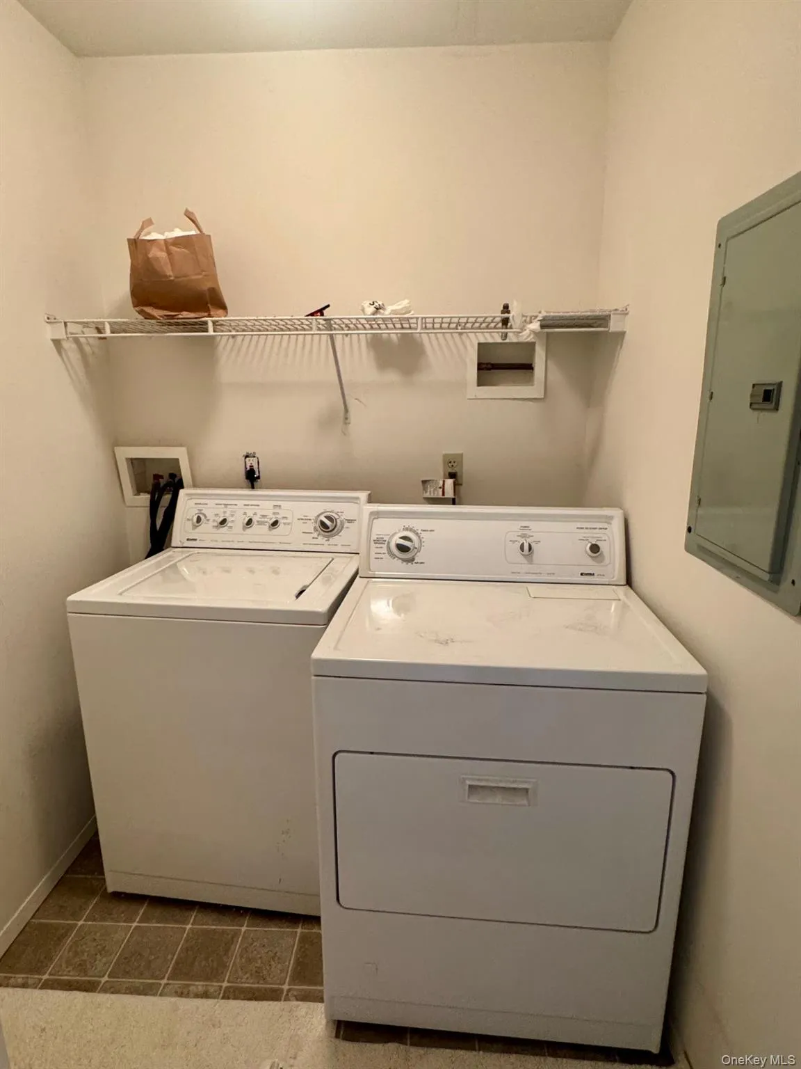 Laundry area featuring electric panel, washing machine and clothes dryer, and tile patterned floors Laundry area featuring electric panel, washing machine and clothes dryer, and tile patterned floors