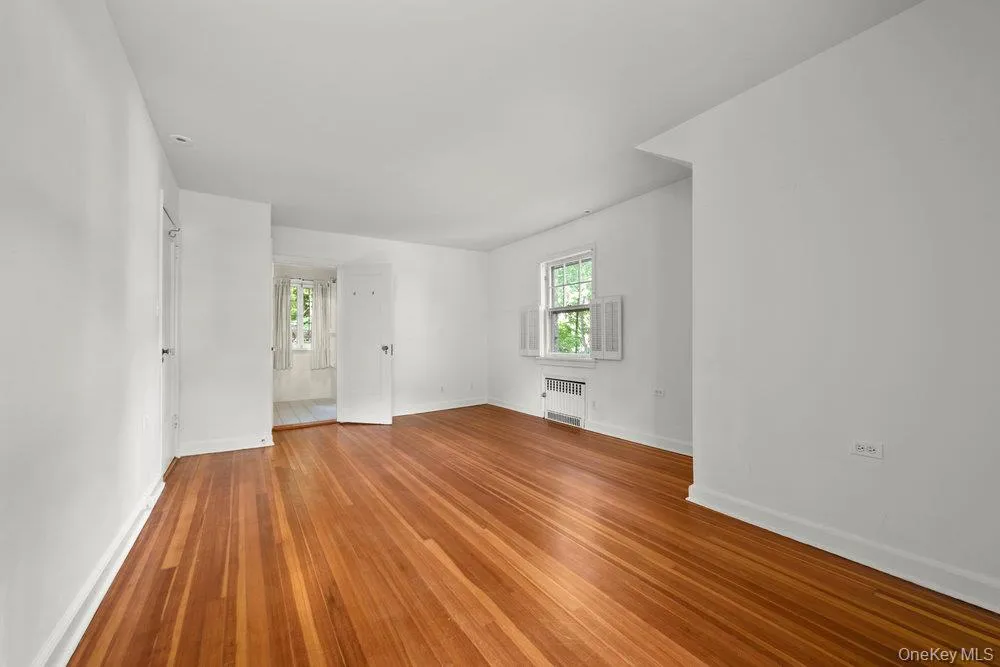Empty room featuring wood finished floors and radiator heating unit Empty room featuring wood finished floors and radiator heating unit
