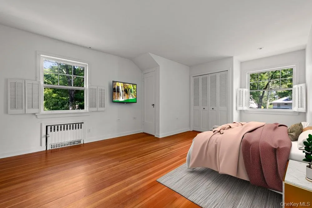 Bedroom with radiator heating unit, wood finished floors, and a closet Bedroom with radiator heating unit, wood finished floors, and a closet