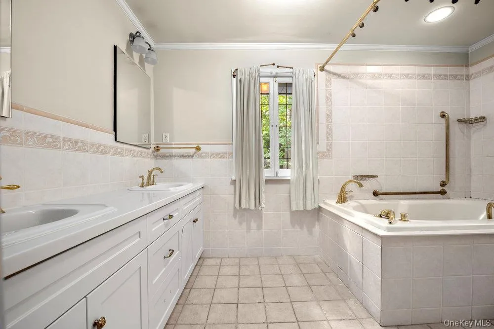 Full bath with tile walls, crown molding, double vanity, light tile patterned floors, and wainscoting Full bath with tile walls, crown molding, double vanity, light tile patterned floors, and wainscoting