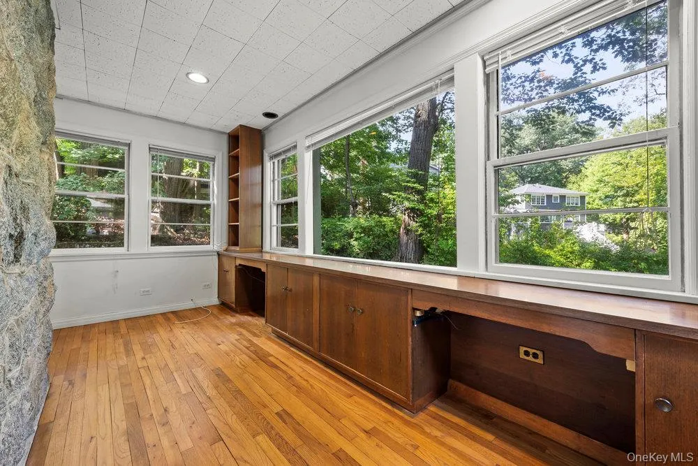Unfurnished sunroom with built in desk and view of scattered trees Unfurnished sunroom with built in desk and view of scattered trees