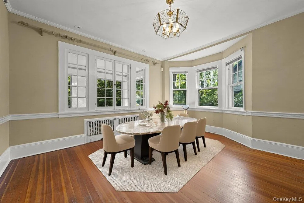 Dining space with hardwood / wood-style flooring, plenty of natural light, crown molding, radiator heating unit, and a chandelier Dining space with hardwood / wood-style flooring, plenty of natural light, crown molding, radiator heating unit, and a chandelier