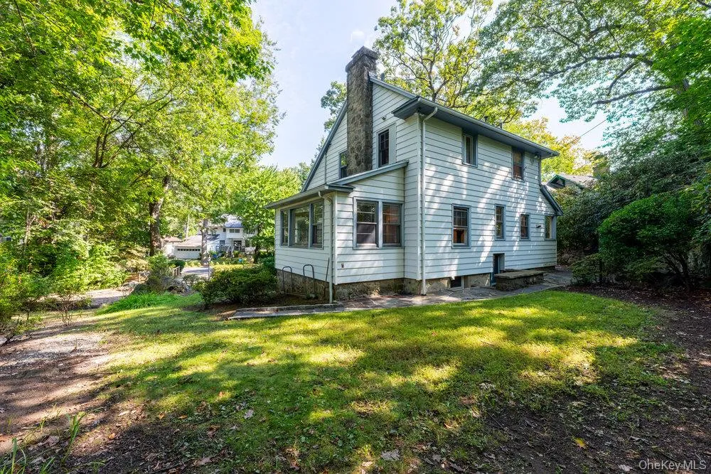 Rear view of house featuring a chimney and a yard Rear view of house featuring a chimney and a yard
