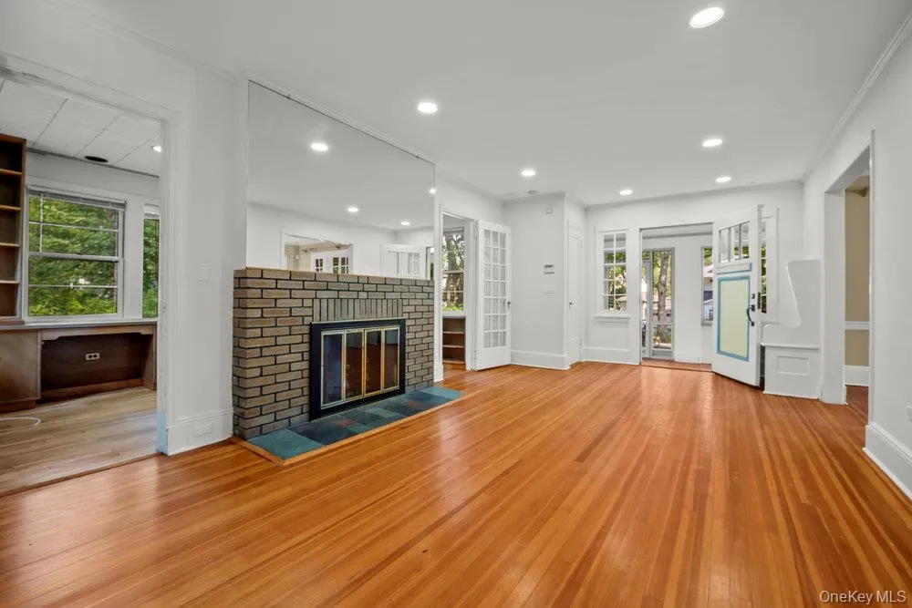 Unfurnished living room featuring hardwood / wood-style floors, a brick fireplace, and recessed lighting Unfurnished living room featuring hardwood / wood-style floors, a brick fireplace, and recessed lighting
