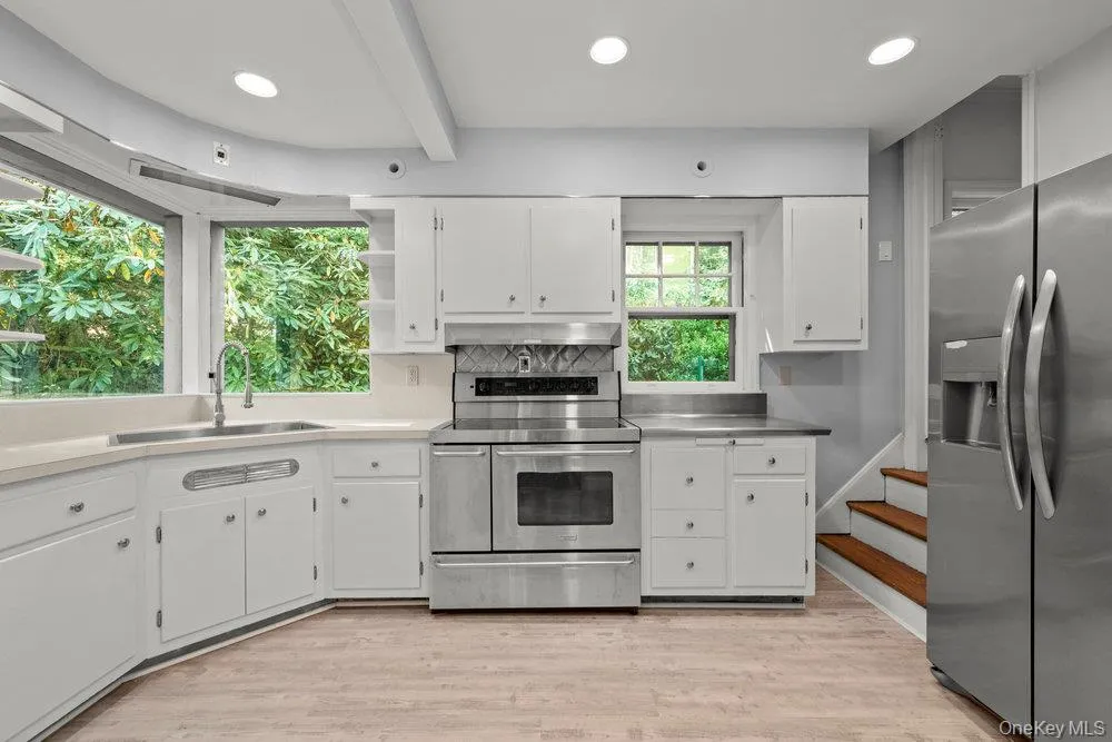 Kitchen with stainless steel appliances, stainless steel countertops, white cabinets, light wood-type flooring, and recessed lighting Kitchen with stainless steel appliances, stainless steel countertops, white cabinets, light wood-type flooring, and recessed lighting