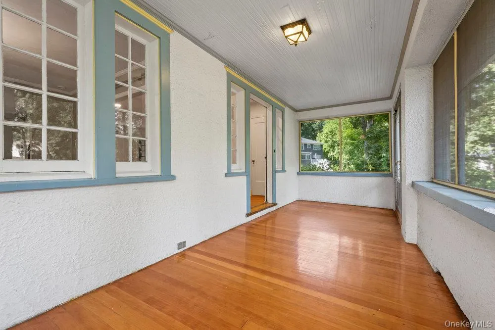 Unfurnished sunroom featuring a textured wall and wood finished floors Unfurnished sunroom featuring a textured wall and wood finished floors