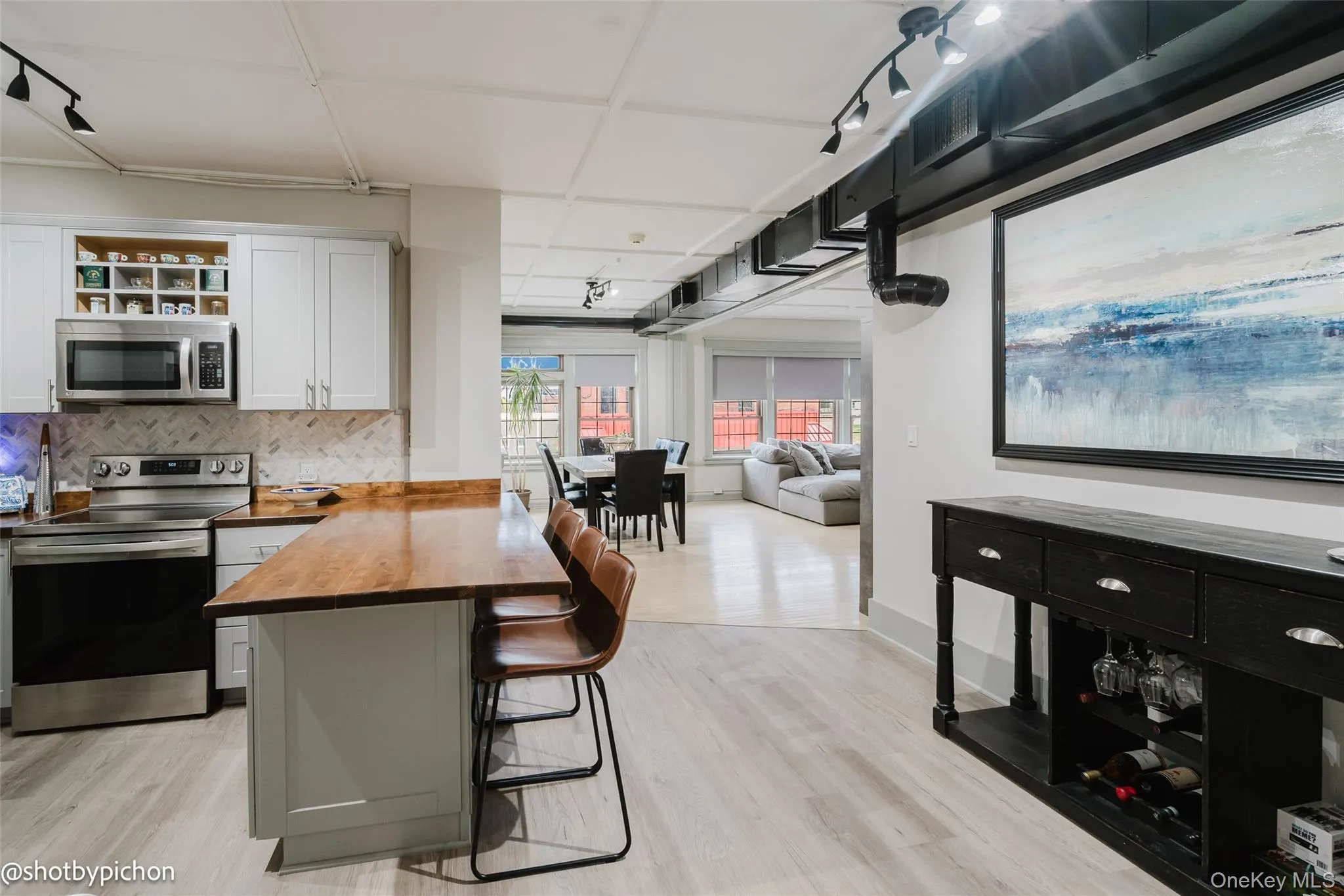 Kitchen with a kitchen breakfast bar, wood counters, stainless steel appliances, decorative backsplash, and light wood-type flooring Kitchen with a kitchen breakfast bar, wood counters, stainless steel appliances, decorative backsplash, and light wood-type flooring