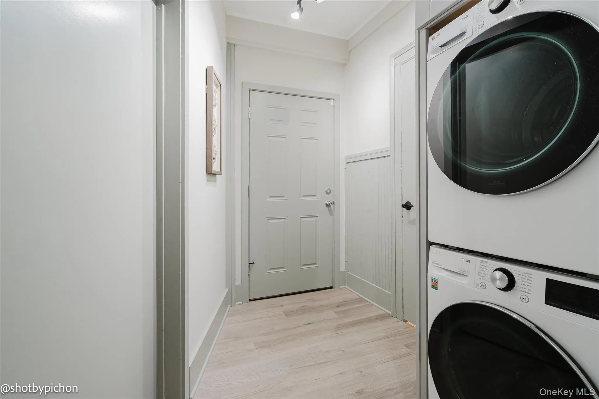 Laundry featuring stacked washer / drying machine and light wood-type flooring Laundry featuring stacked washer / drying machine and light wood-type flooring