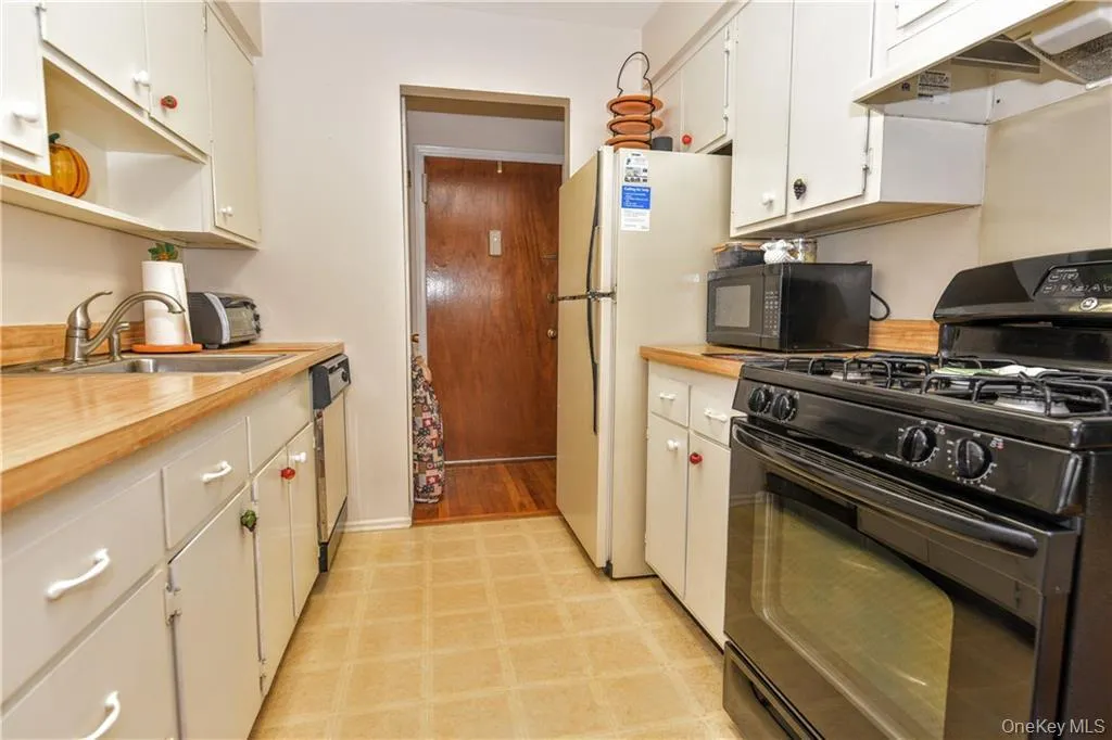 Kitchen with black appliances, light countertops, under cabinet range hood, and white cabinets Kitchen with black appliances, light countertops, under cabinet range hood, and white cabinets