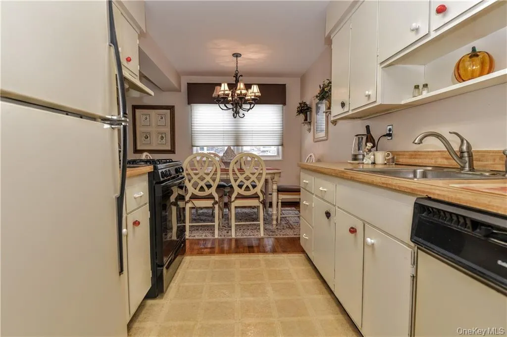 Kitchen featuring white appliances, light countertops, open shelves, pendant lighting, and a chandelier Kitchen featuring white appliances, light countertops, open shelves, pendant lighting, and a chandelier