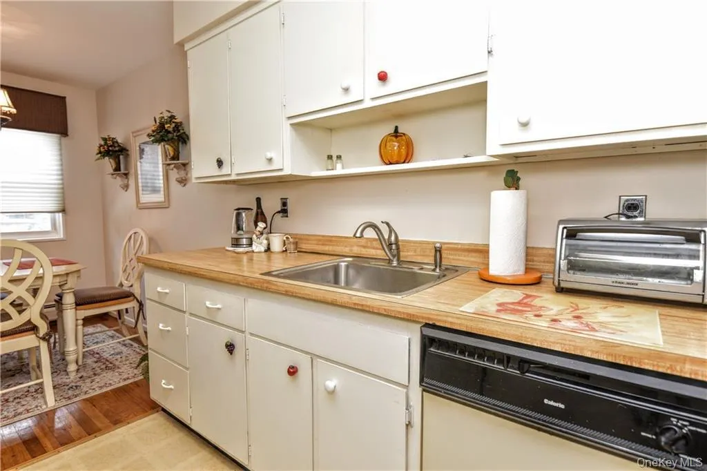 Kitchen featuring open shelves, light countertops, dishwasher, light wood-type flooring, and white cabinets Kitchen featuring open shelves, light countertops, dishwasher, light wood-type flooring, and white cabinets