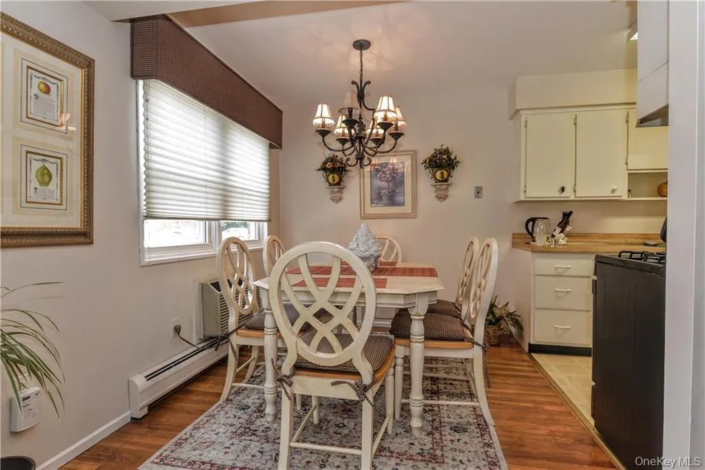 Dining space with baseboard heating, light wood-style flooring, a chandelier, and a wall mounted AC Dining space with baseboard heating, light wood-style flooring, a chandelier, and a wall mounted AC