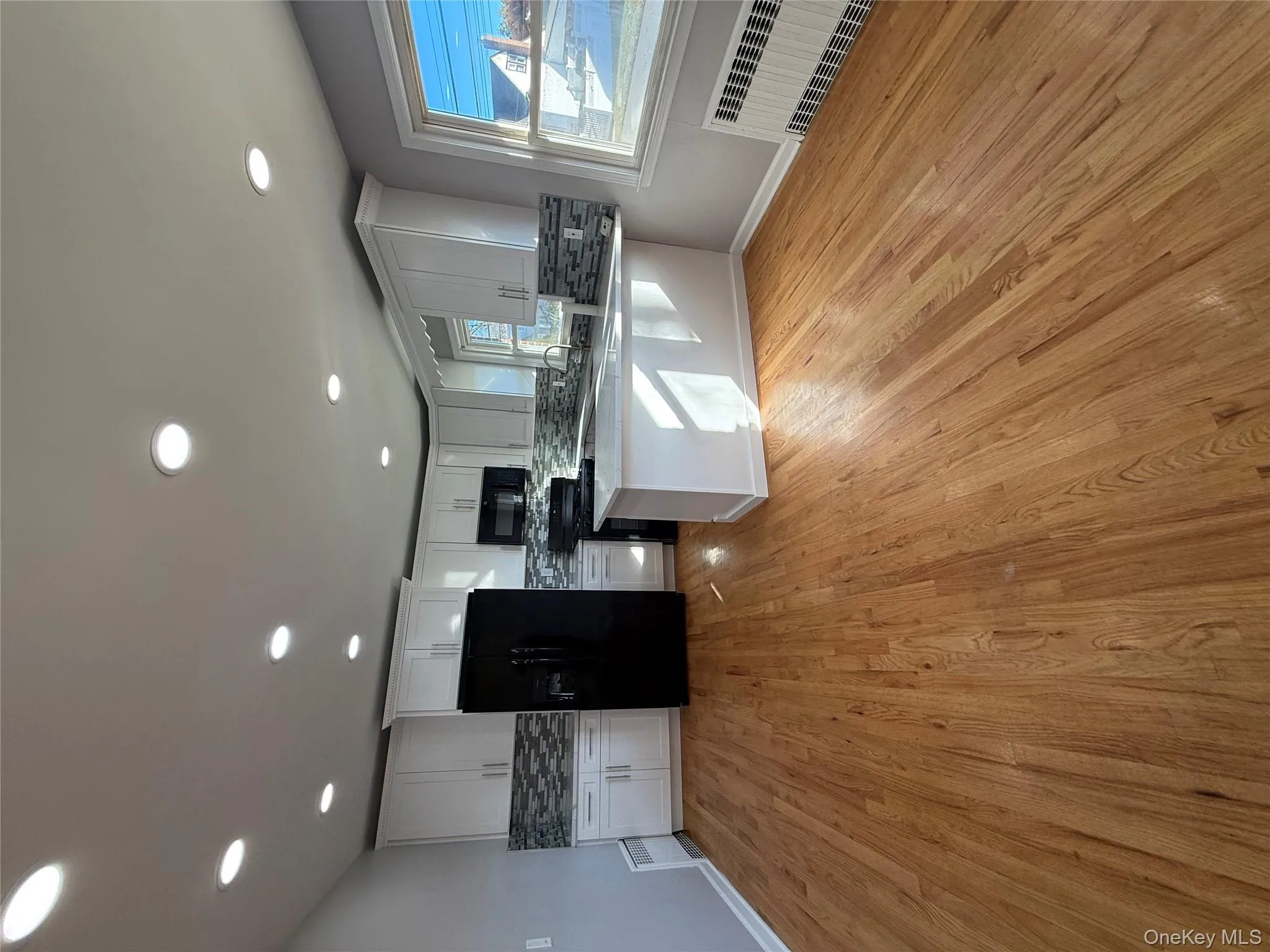Kitchen featuring backsplash, refrigerator, radiator, white cabinetry, and recessed lighting Kitchen featuring backsplash, refrigerator, radiator, white cabinetry, and recessed lighting
