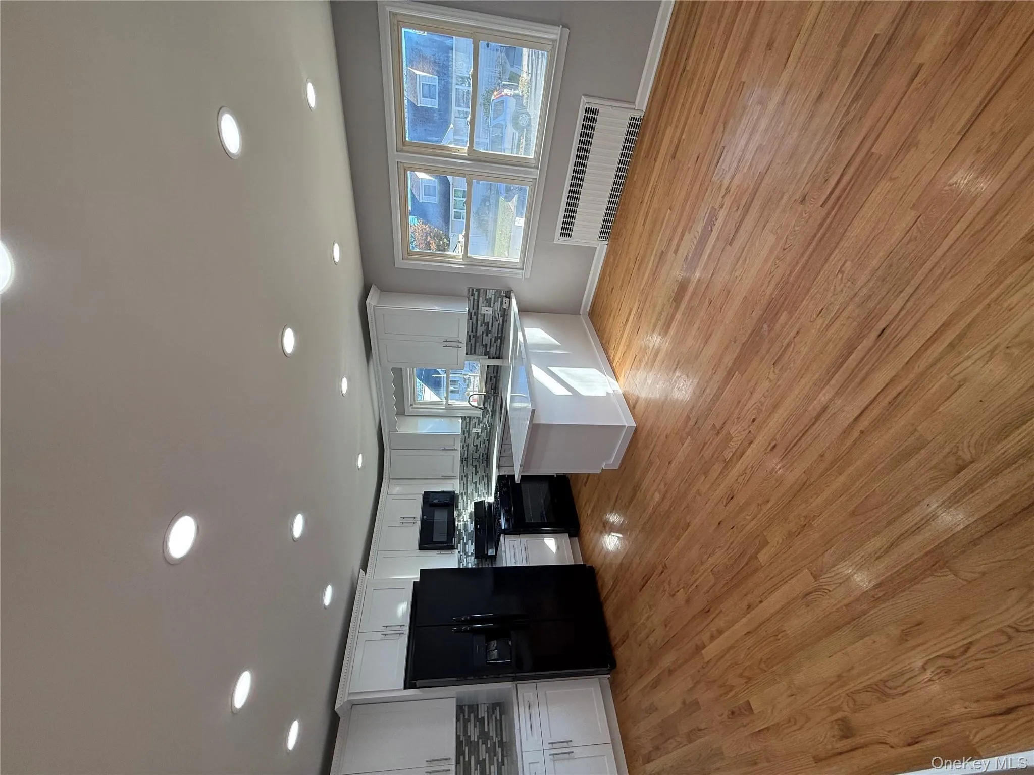 Kitchen with refrigerator, a peninsula, radiator, stove, and white cabinetry Kitchen with refrigerator, a peninsula, radiator, stove, and white cabinetry