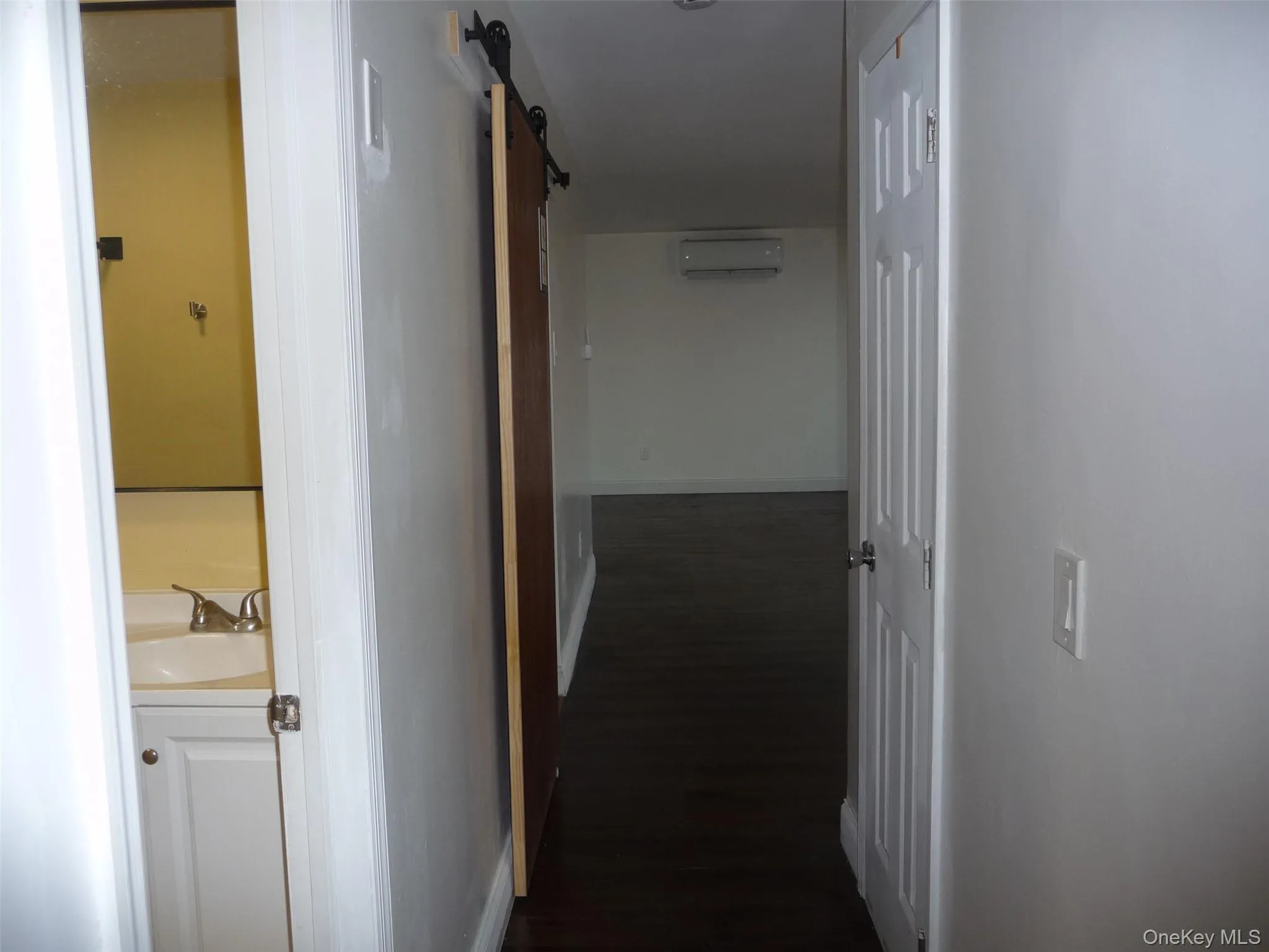 Hallway featuring a barn door, dark wood-style floors, and a wall unit AC Hallway featuring a barn door, dark wood-style floors, and a wall unit AC