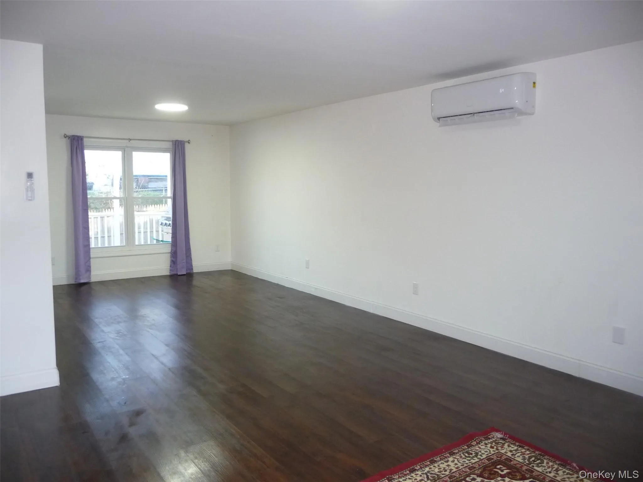 Spare room featuring dark wood-style flooring and an AC wall unit Spare room featuring dark wood-style flooring and an AC wall unit