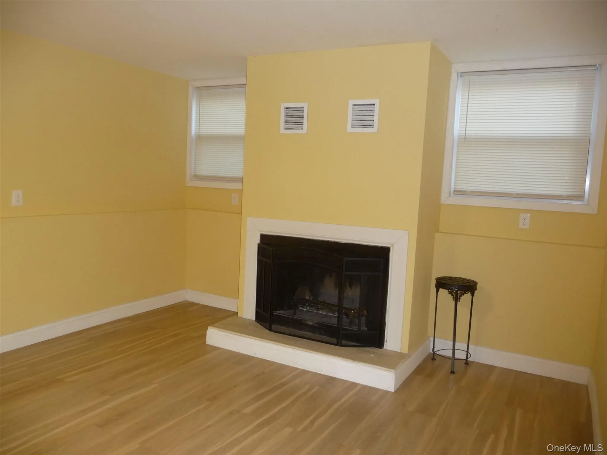 Unfurnished living room featuring a fireplace with raised hearth and light wood-style flooring Unfurnished living room featuring a fireplace with raised hearth and light wood-style flooring