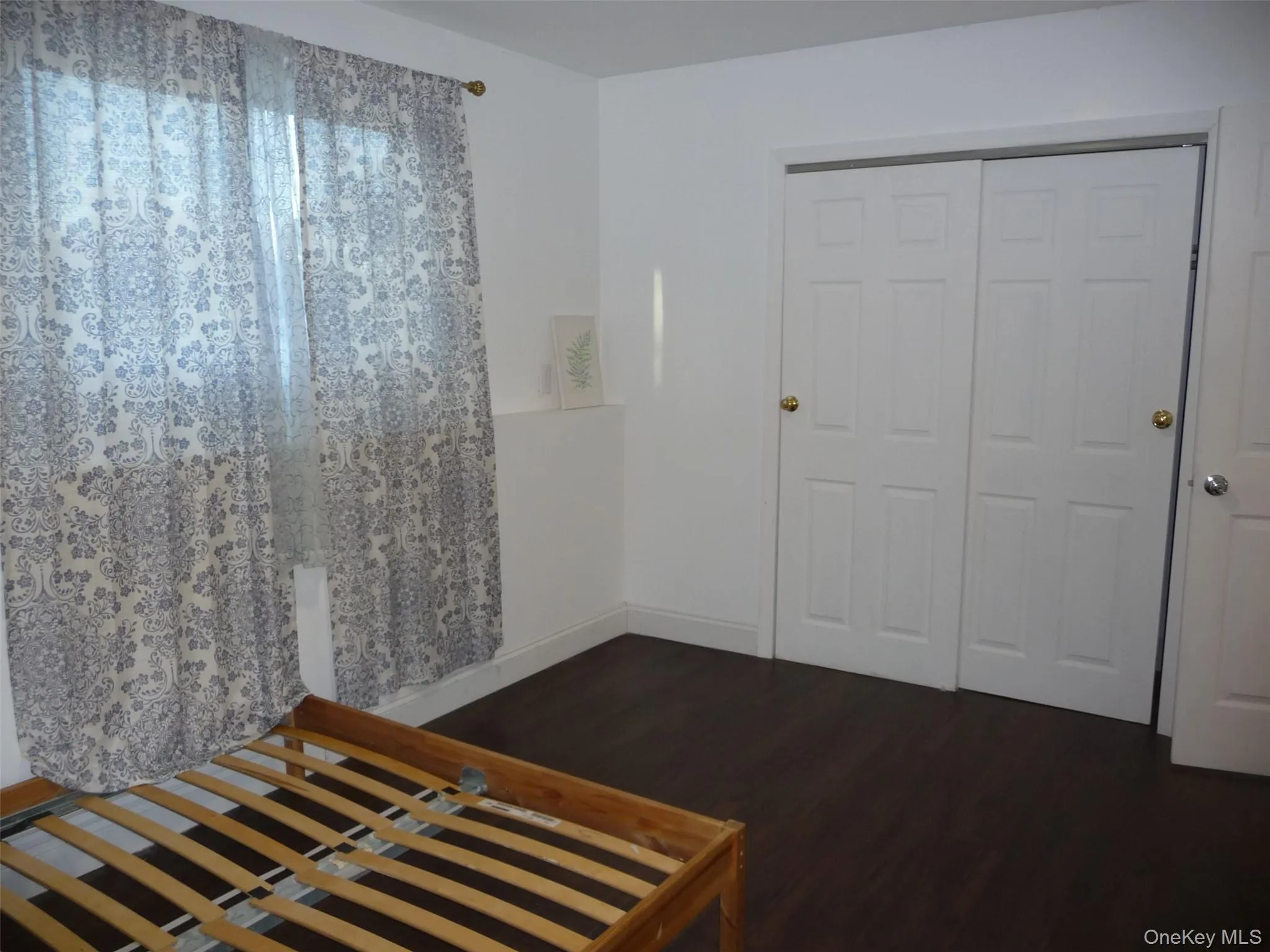 Unfurnished bedroom featuring dark wood-type flooring and a closet Unfurnished bedroom featuring dark wood-type flooring and a closet