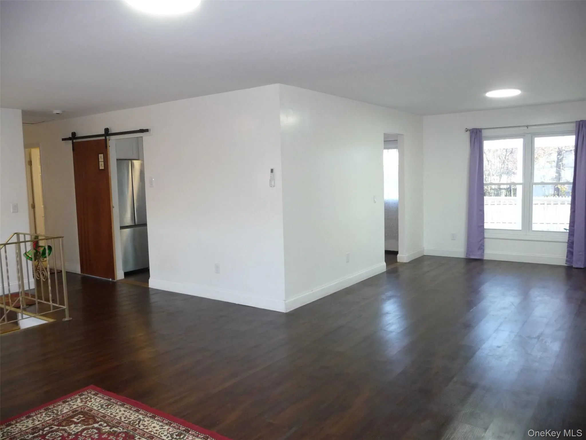 Spare room featuring a barn door and dark wood-type flooring Spare room featuring a barn door and dark wood-type flooring