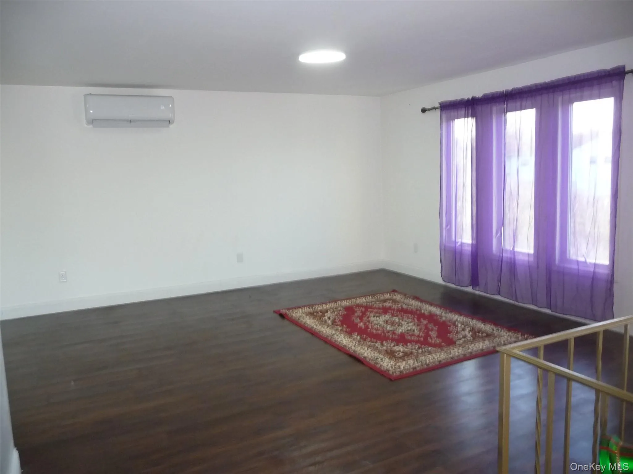 Unfurnished room with dark wood-style flooring and a wall unit AC Unfurnished room with dark wood-style flooring and a wall unit AC