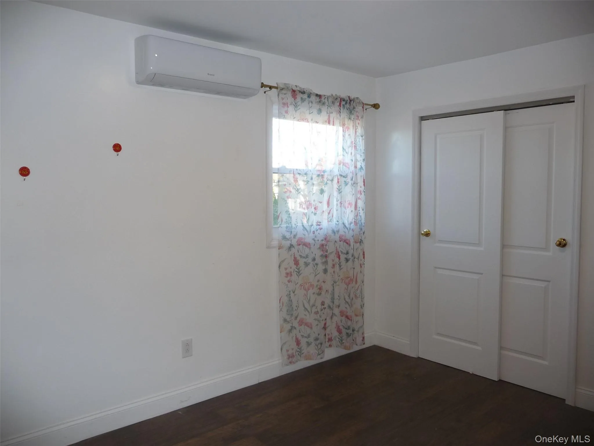 Unfurnished bedroom with a closet, dark wood finished floors, and a wall mounted AC Unfurnished bedroom with a closet, dark wood finished floors, and a wall mounted AC