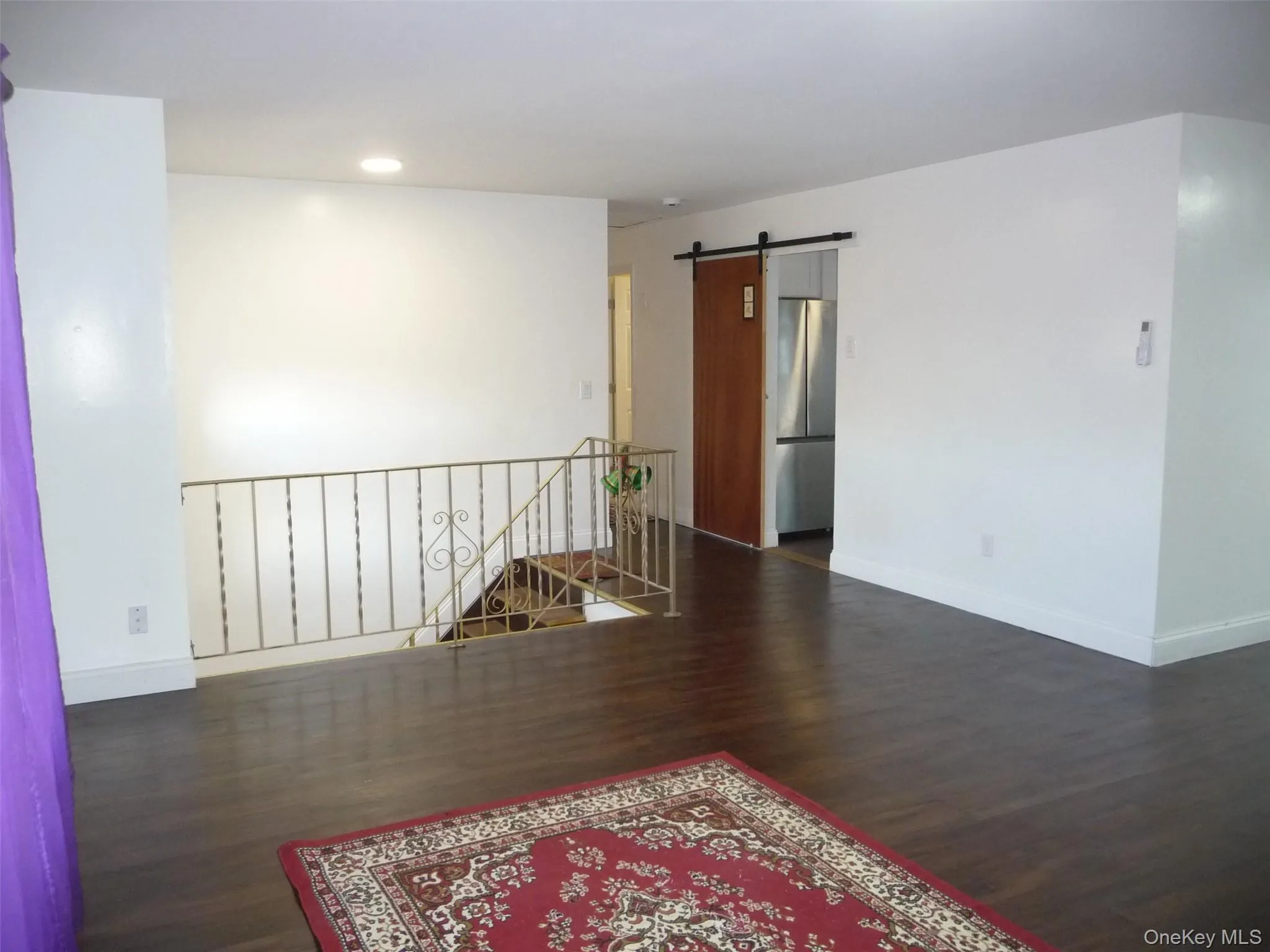 Empty room featuring a barn door, dark wood finished floors, and recessed lighting Empty room featuring a barn door, dark wood finished floors, and recessed lighting