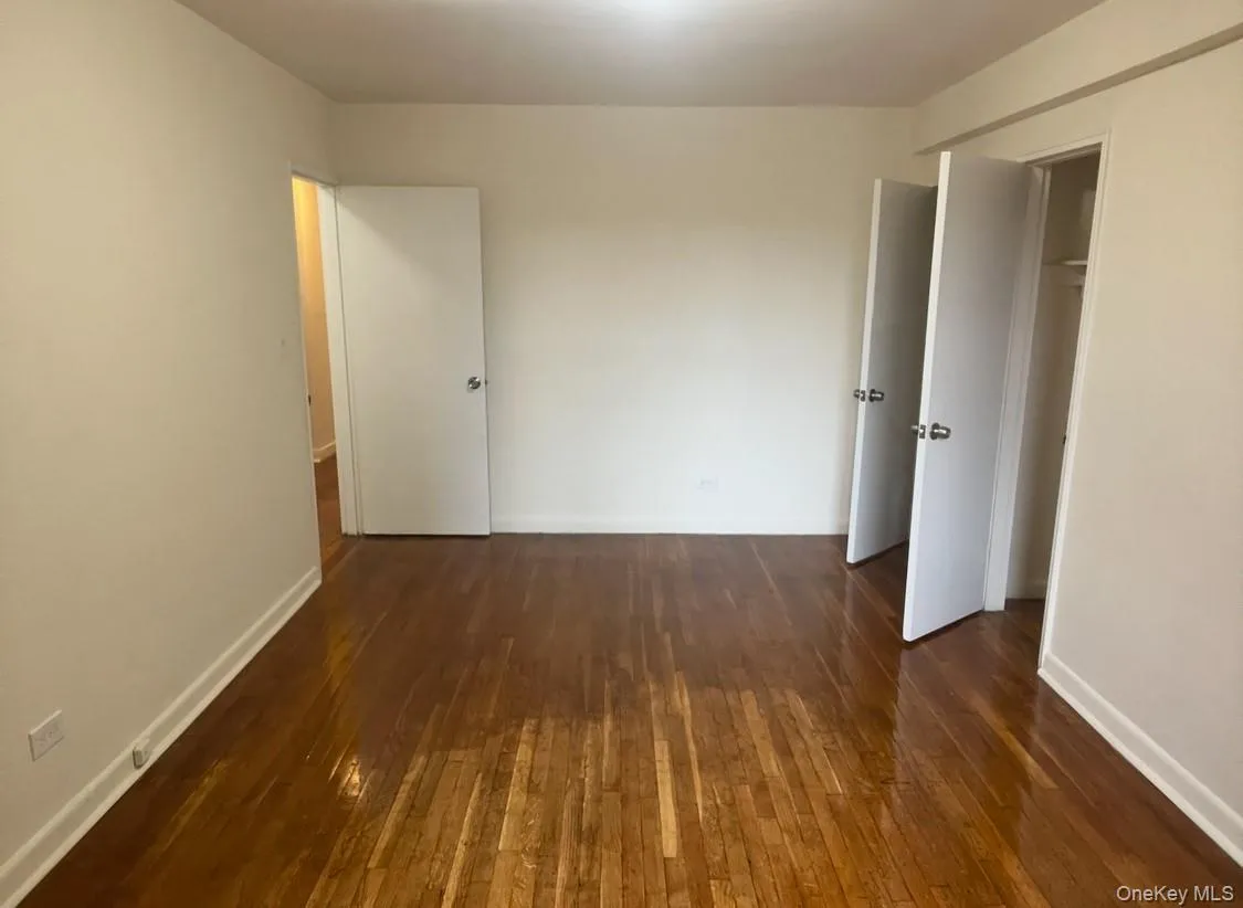 Unfurnished bedroom with dark wood finished floors and baseboards Unfurnished bedroom with dark wood finished floors and baseboards