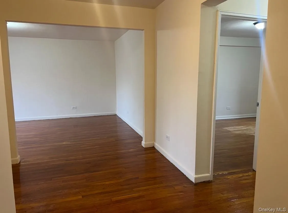 Unfurnished room with dark wood-style floors and baseboards Unfurnished room with dark wood-style floors and baseboards