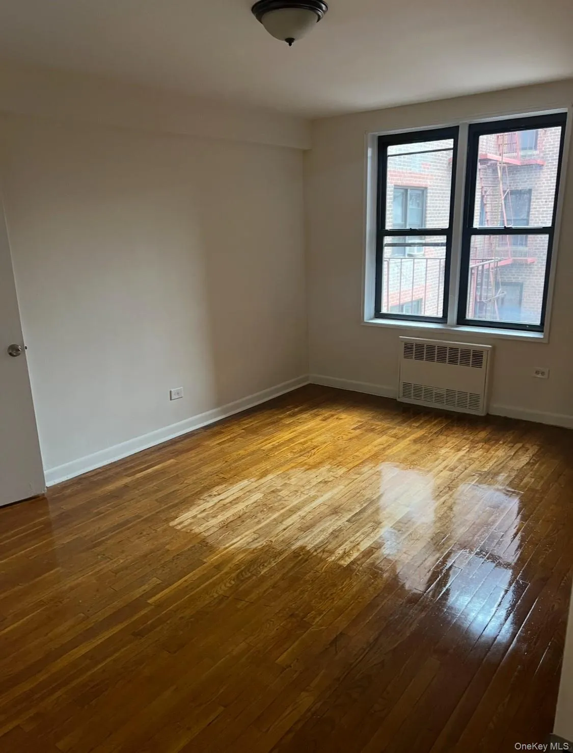 Spare room featuring light wood-style floors and radiator heating unit Spare room featuring light wood-style floors and radiator heating unit