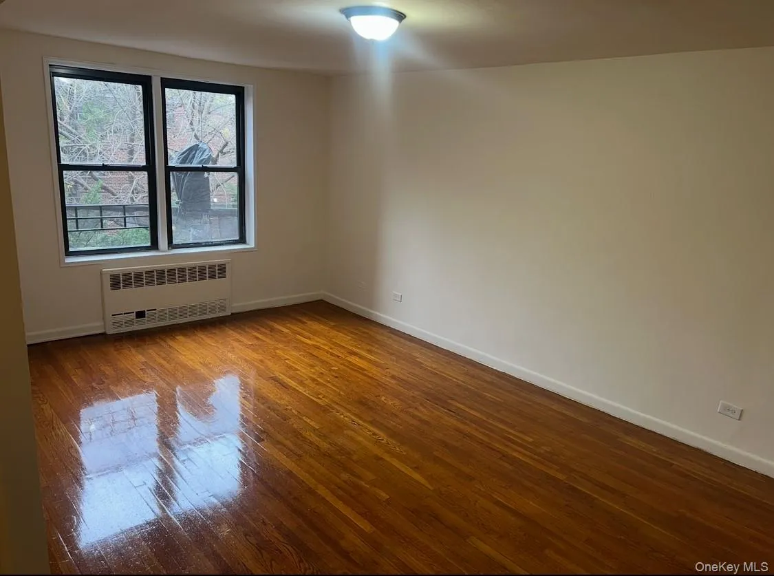 Unfurnished room with dark wood finished floors and radiator heating unit Unfurnished room with dark wood finished floors and radiator heating unit