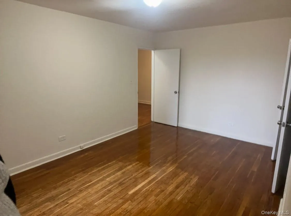 Spare room with dark wood-style floors and baseboards Spare room with dark wood-style floors and baseboards