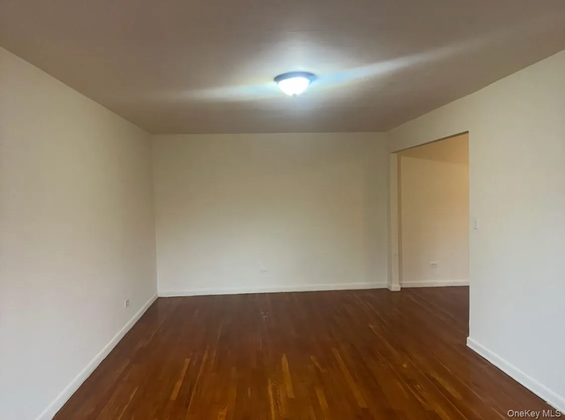 Unfurnished room featuring dark wood-style floors and baseboards Unfurnished room featuring dark wood-style floors and baseboards