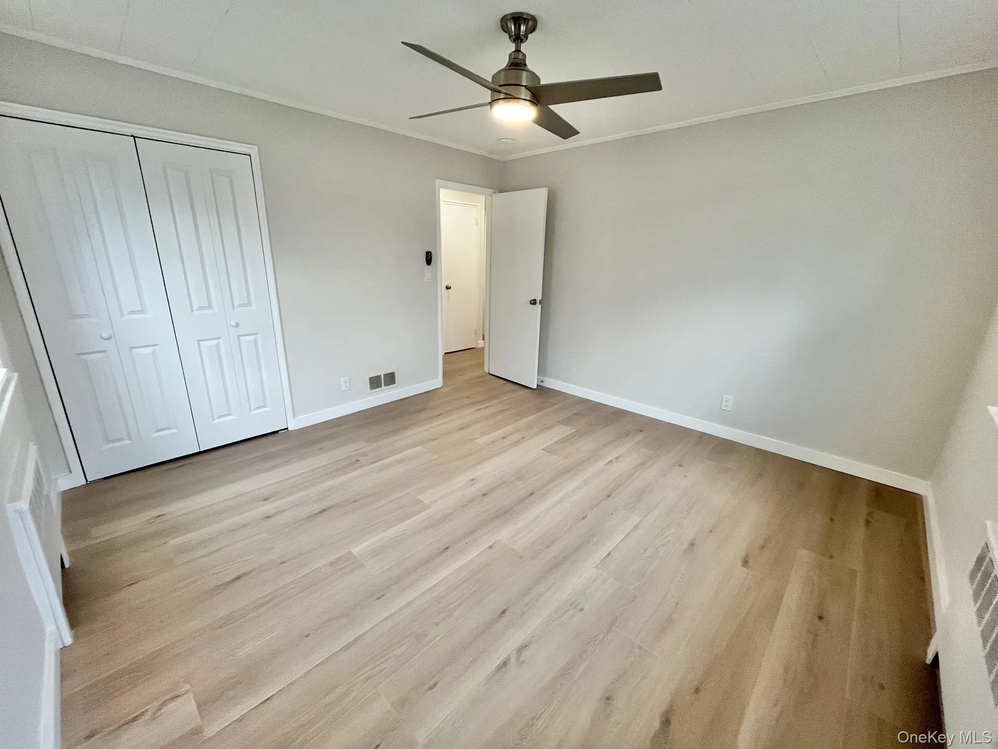 Unfurnished bedroom with light wood-type flooring, ornamental molding, a ceiling fan, and a closet Unfurnished bedroom with light wood-type flooring, ornamental molding, a ceiling fan, and a closet