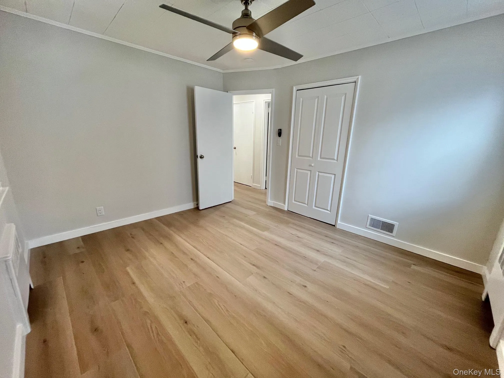 Unfurnished bedroom with light wood-type flooring, a ceiling fan, a closet, and crown molding Unfurnished bedroom with light wood-type flooring, a ceiling fan, a closet, and crown molding