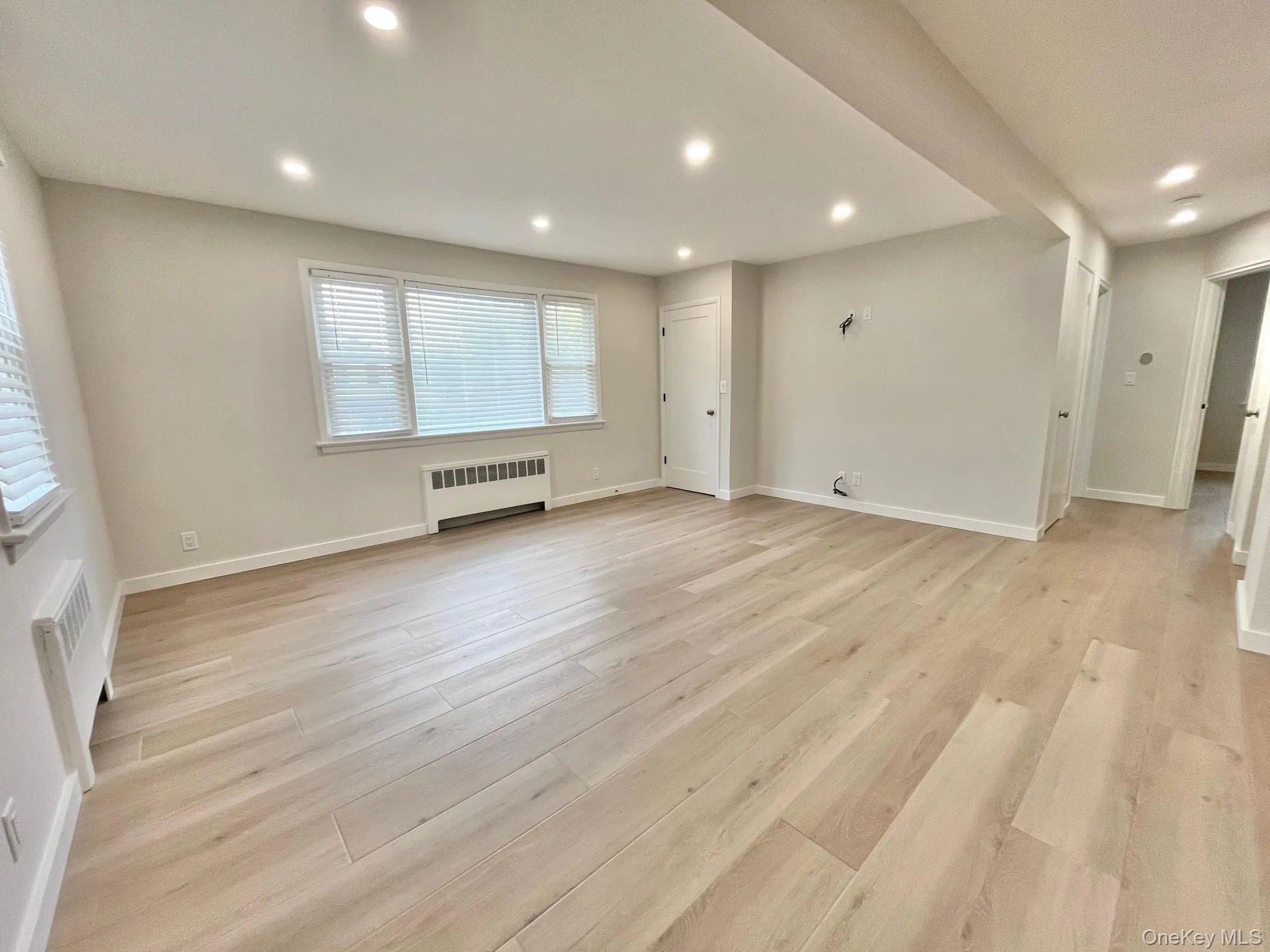 Unfurnished room featuring radiator heating unit, recessed lighting, and light wood finished floors Unfurnished room featuring radiator heating unit, recessed lighting, and light wood finished floors