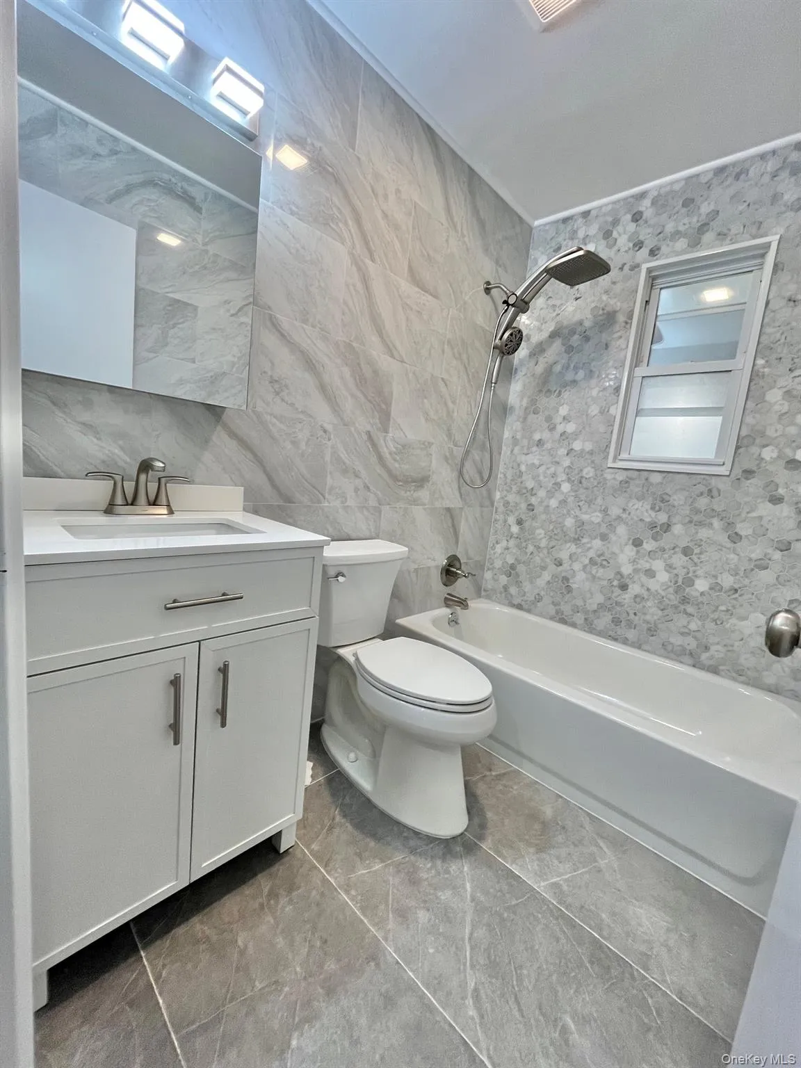 Bathroom featuring tile walls, vanity, and washtub / shower combination Bathroom featuring tile walls, vanity, and washtub / shower combination