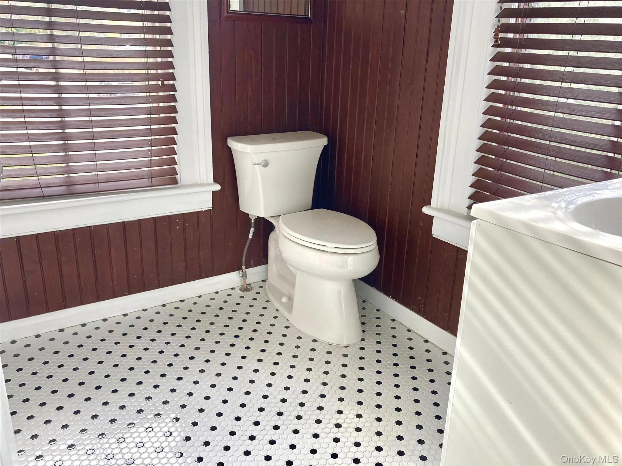 Bathroom with tile patterned floors, wood walls, and toilet Bathroom with tile patterned floors, wood walls, and toilet