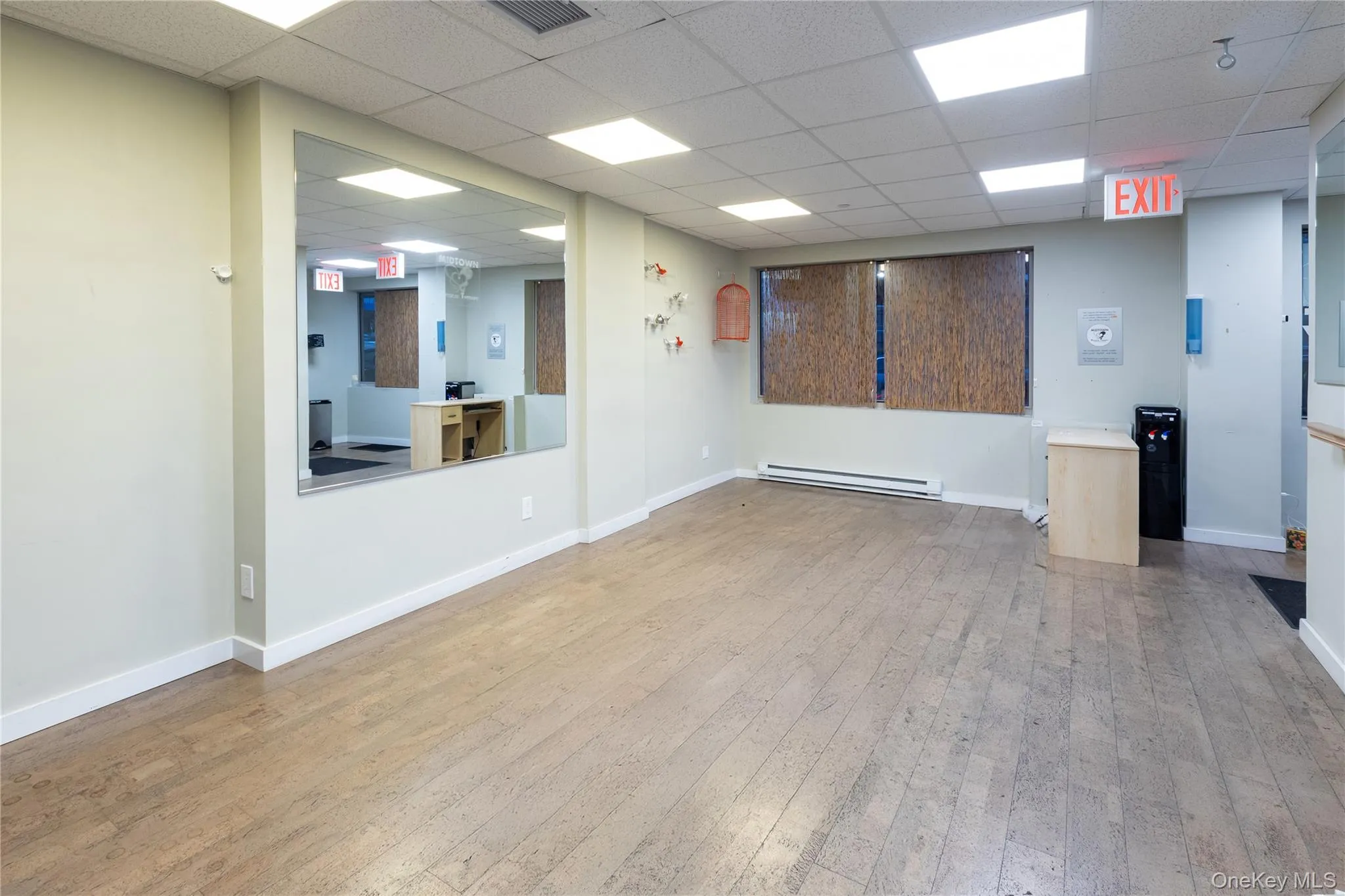 Unfurnished room with light wood-type flooring, a baseboard heating unit, and a drop ceiling Unfurnished room with light wood-type flooring, a baseboard heating unit, and a drop ceiling