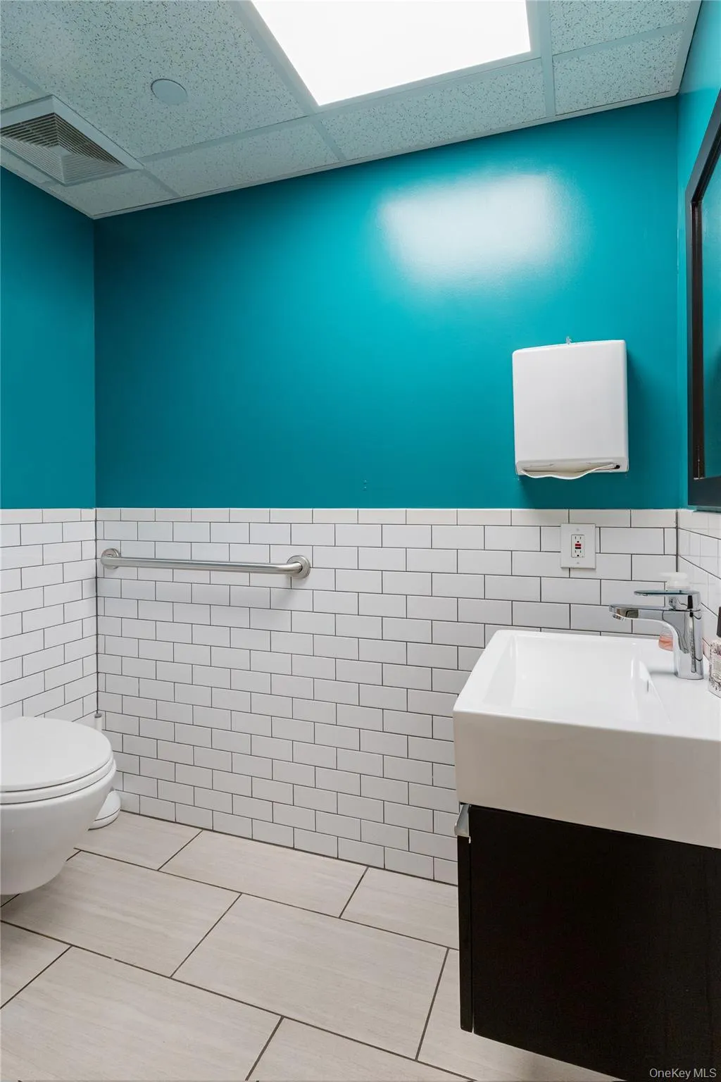 Half bathroom featuring a drop ceiling, tile walls, wainscoting, vanity, and tile patterned flooring Half bathroom featuring a drop ceiling, tile walls, wainscoting, vanity, and tile patterned flooring
