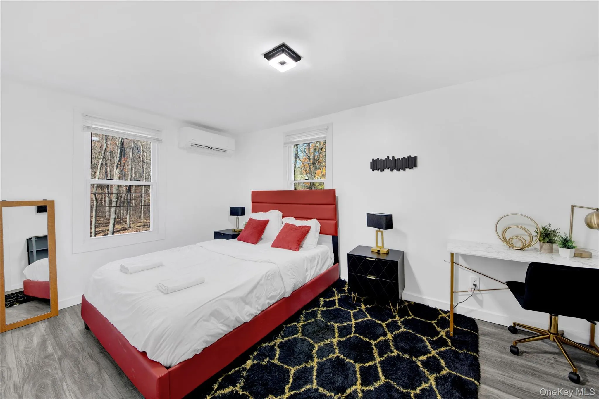 Bedroom featuring wood finished floors, multiple windows, a wall unit AC, and an office area Bedroom featuring wood finished floors, multiple windows, a wall unit AC, and an office area