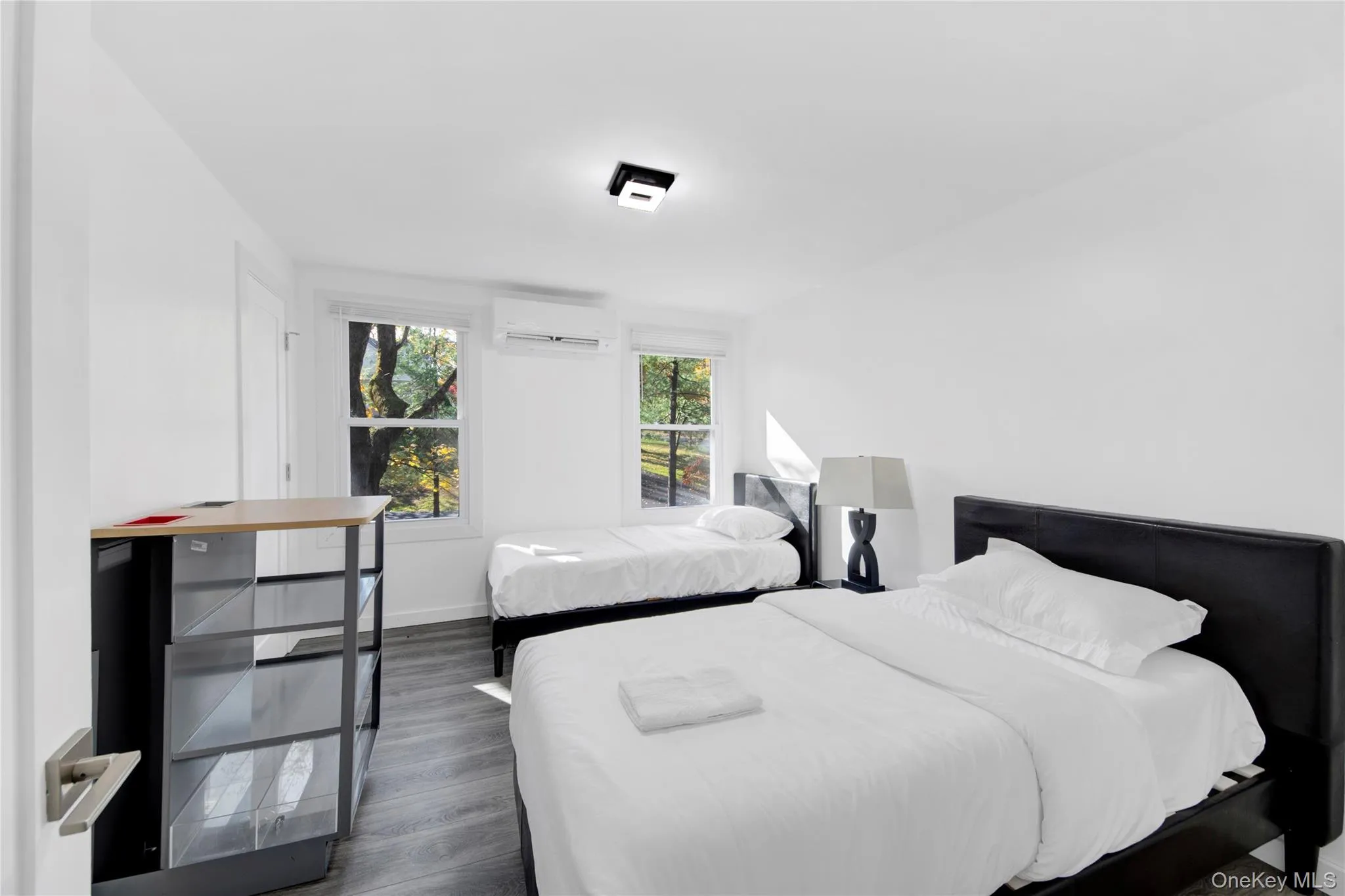 Bedroom featuring dark wood-style flooring and a wall mounted air conditioner Bedroom featuring dark wood-style flooring and a wall mounted air conditioner