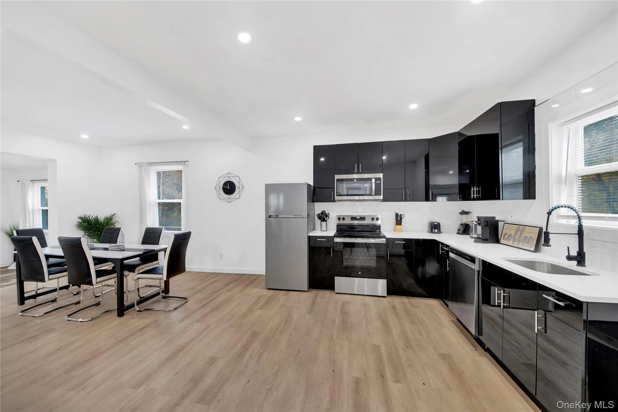 Kitchen featuring dark cabinets, appliances with stainless steel finishes, recessed lighting, backsplash, and light wood-type flooring Kitchen featuring dark cabinets, appliances with stainless steel finishes, recessed lighting, backsplash, and light wood-type flooring
