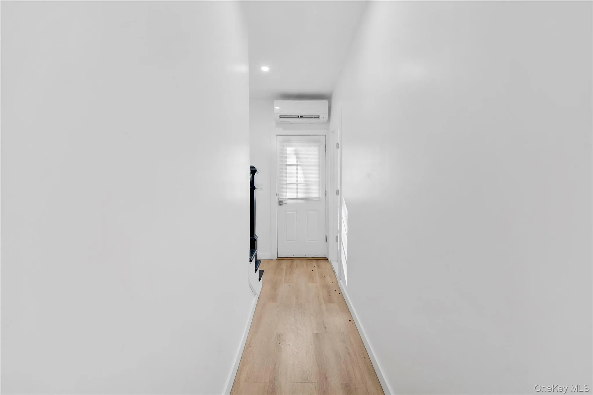 Hallway with light wood-style flooring, a wall mounted air conditioner, and recessed lighting Hallway with light wood-style flooring, a wall mounted air conditioner, and recessed lighting