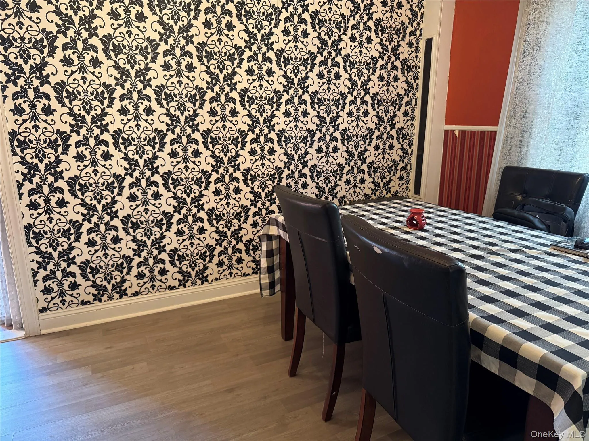 Dining room with light wood-style flooring and wallpapered walls Dining room with light wood-style flooring and wallpapered walls