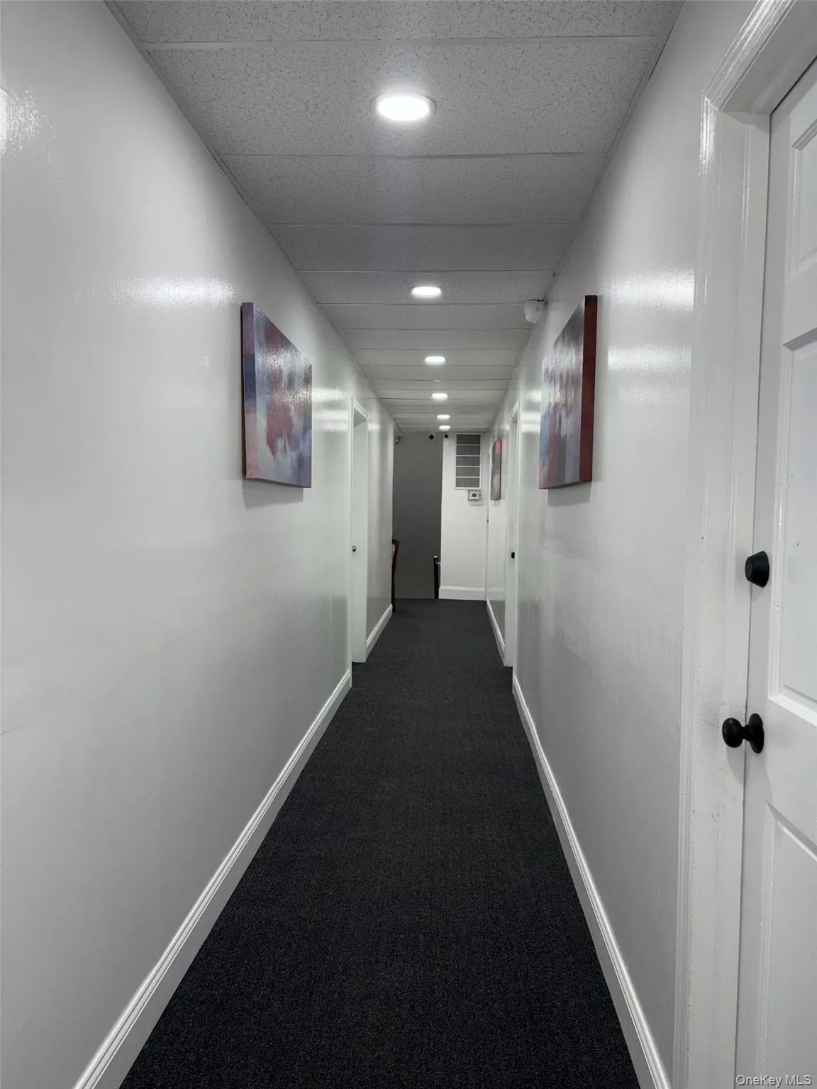 Corridor featuring dark colored carpet and a drop ceiling Corridor featuring dark colored carpet and a drop ceiling