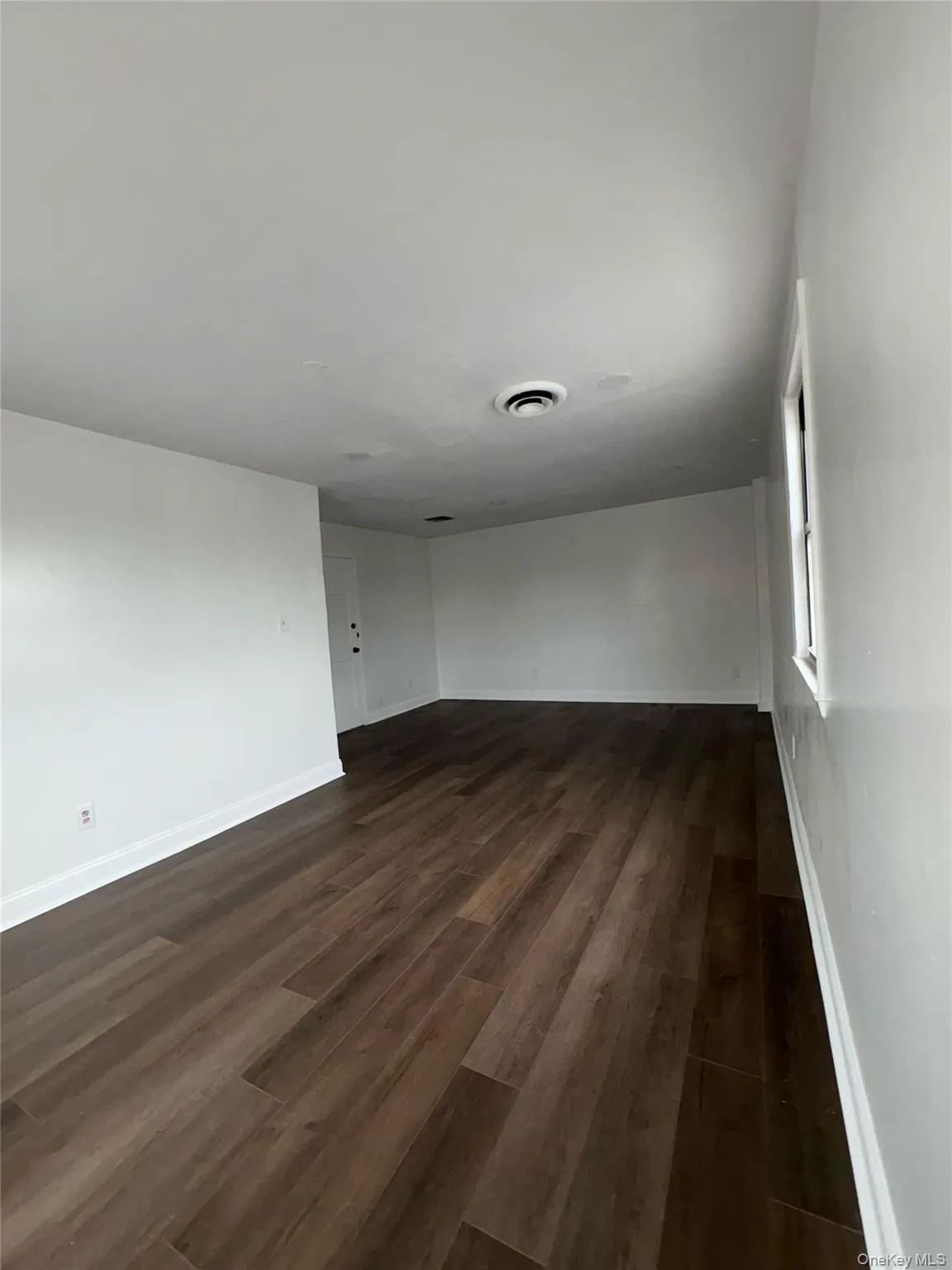 Empty room featuring dark wood-style flooring and baseboards Empty room featuring dark wood-style flooring and baseboards