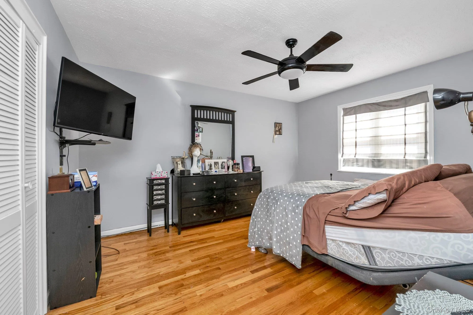 Bedroom with light wood-style floors, a textured ceiling, a ceiling fan, and a closet Bedroom with light wood-style floors, a textured ceiling, a ceiling fan, and a closet