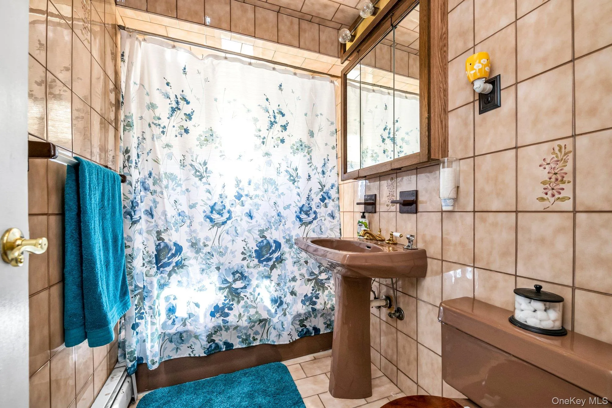 Bathroom with tile walls, tile patterned flooring, baseboard heating, and shower / tub combo Bathroom with tile walls, tile patterned flooring, baseboard heating, and shower / tub combo