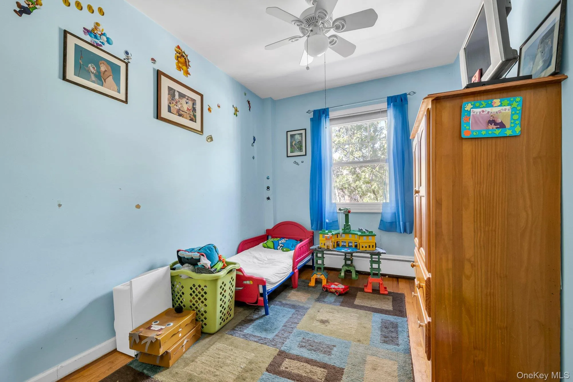 Bedroom with wood finished floors, a ceiling fan, and a baseboard heating unit Bedroom with wood finished floors, a ceiling fan, and a baseboard heating unit