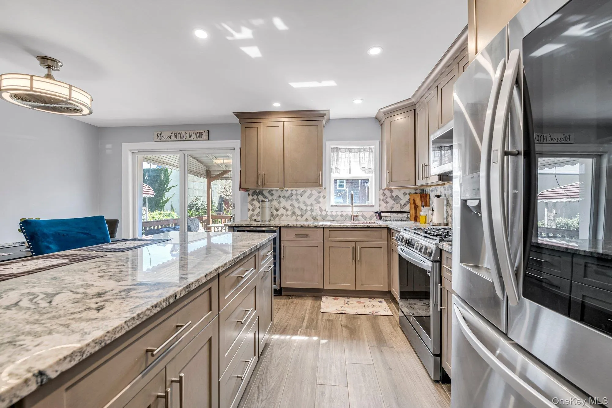 Kitchen featuring appliances with stainless steel finishes, light stone counters, tasteful backsplash, recessed lighting, and light wood-type flooring Kitchen featuring appliances with stainless steel finishes, light stone counters, tasteful backsplash, recessed lighting, and light wood-type flooring